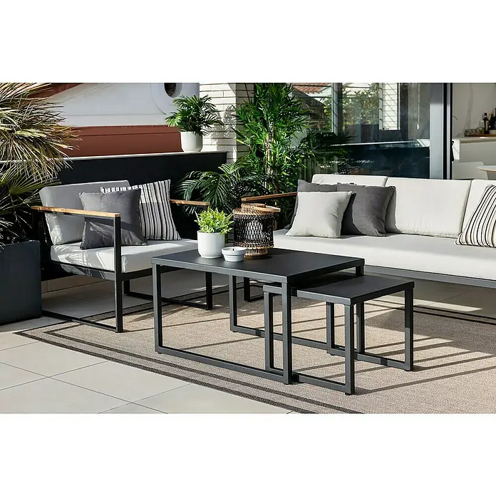 SENSUM Conjunto de muebles Inari - 5 pzs., Aluminio, Negro - Elegante escena exterior con un moderno conjunto de salón y una mesa nido negra sobre una alfombra.