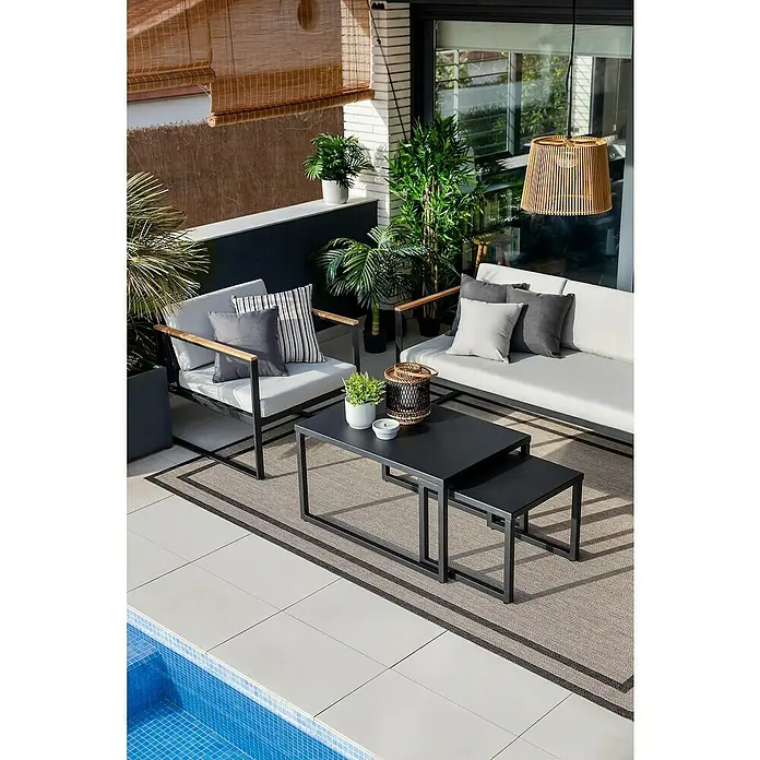 SENSUM Conjunto de muebles Inari - 5 pzs., Aluminio, Negro - Un moderno espacio exterior con mesas nido negras como punto focal, complementado con muebles elegantes y plantas exuberantes.