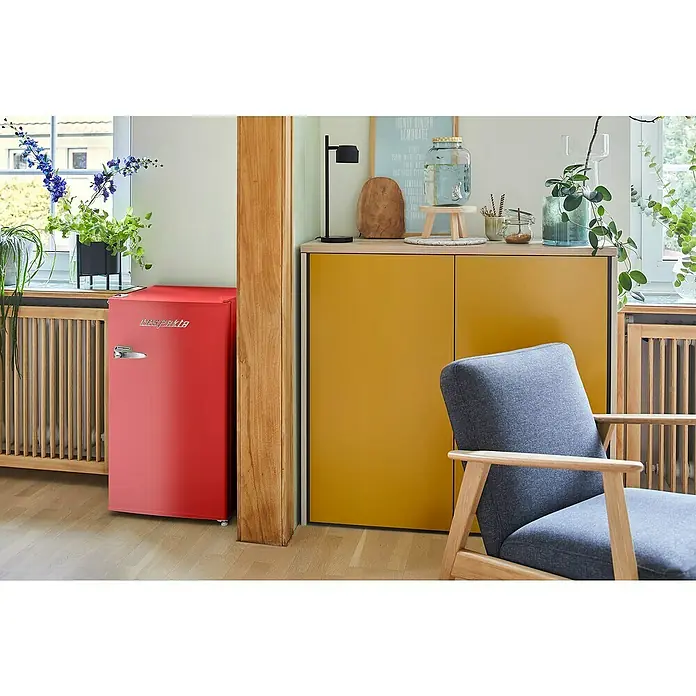 Respekta Vollraumkühlschrank Rico - Nutzinhalt Gesamt: 92 l, 44,7 x 47,4 x 83,1 cm, Rot - Roter Klarstein Mini-Kühlschrank neben einem gelben Schrank und einem grauen Sessel in einem hellen Raum.