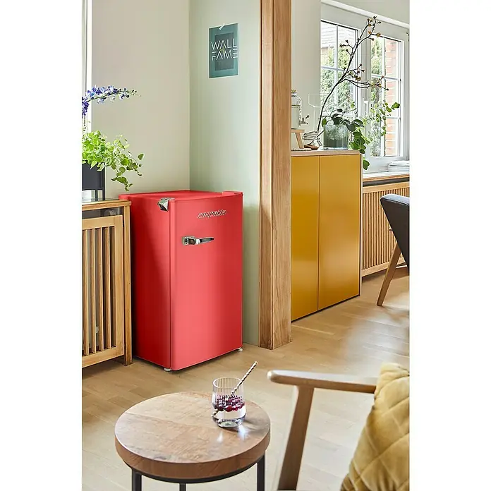 Respekta Vollraumkühlschrank Rico - Nutzinhalt Gesamt: 92 l, 44,7 x 47,4 x 83,1 cm, Rot - Ein roter Minikühlschrank der Marke "Prodprika" steht auf einem Holzboden in einem modern eingerichteten Wohnzimmer.