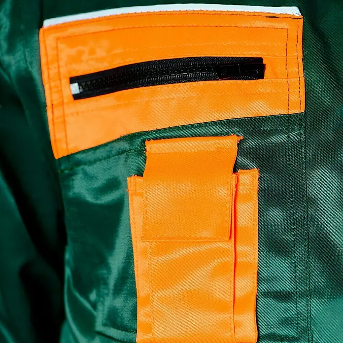 Forstblouson 4in1 - Grün/Orange, XXL - Detailaufnahme einer grünen Arbeitskleidung mit orangefarbenen Taschen und einem schwarzen Reißverschluss.