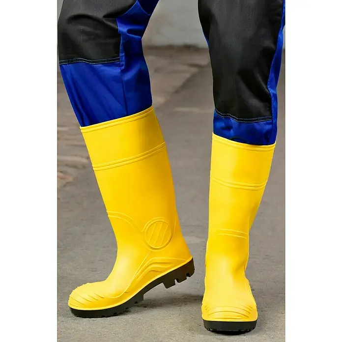 Sicherheitsstiefel - Schuhgröße: 43, S5 - Gelbe Gummistiefel für den Arbeitsschutz mit schwarzer Sohle und mehrfarbiger Arbeitshose. Für sicheren Halt und Schutz vor Nässe.