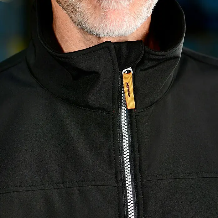 L.Brador Softshell-Jacke 554 P - Schwarz, XS - Nahaufnahme einer schwarzen Softshelljacke mit hohem Kragen und silbernem Reißverschluss mit orangefarbenem Zugband.