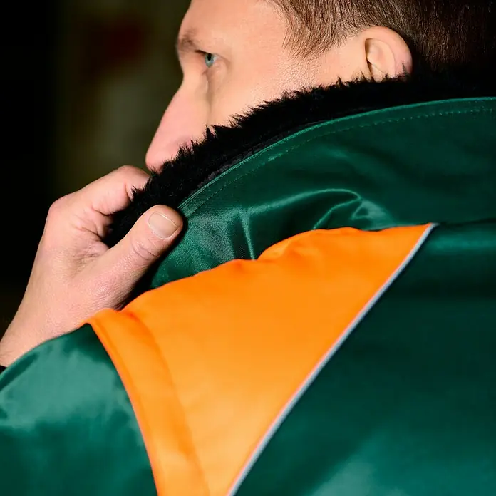 Forstblouson 4in1 - Grün/Orange, XXL - Nahaufnahme einer grünen und orangefarbenen Arbeitsjacke mit Pelzkragen, die einen eleganten und schützenden Stil für professionelle Umgebungen bietet.