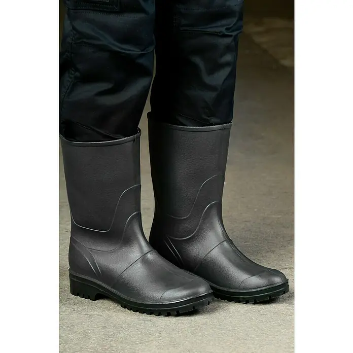 Sicherheitsstiefel - Schuhgröße: 41, Wadenhoch - Nahaufnahme von schwarzen Gummistiefeln mit Hosenbeinen in den Stiefeln. Die Stiefel stehen auf einer grauen Oberfläche.
