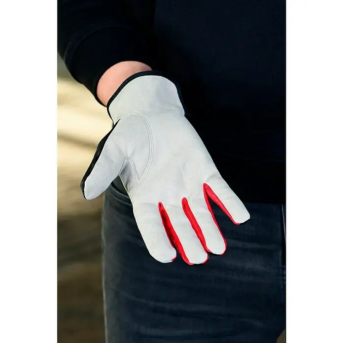 Guide Arbeitshandschuhe 761 - Grau/Schwarz, 11 - Nahaufnahme eines grauen Handschuhs mit roten Fingern und schwarzem Daumen vor einer Person mit schwarzem Hemd und blauen Jeans.