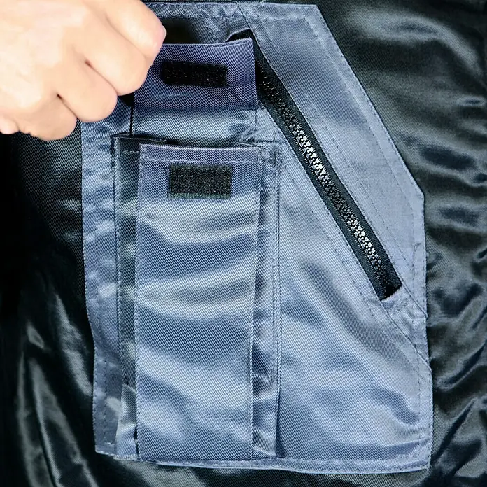 Elutex Piloten-Blouson 4in1 - Schwarz/Grau, M - Nahaufnahme einer Jackentasche mit Reißverschluss und Klettverschluss, die Funktionalität und praktisches Design vereint.