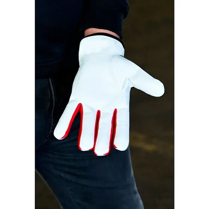 Guide Arbeitshandschuhe 5161 PP - Weiß/Schwarz, 10 - Nahaufnahme eines weißen Handschuhs mit roter Umrandung, getragen von einer Person mit dunkler Kleidung.