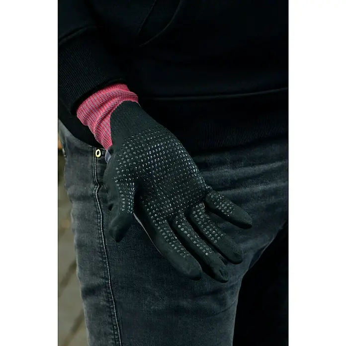 Guide Arbeitshandschuhe 582 - Grau/Schwarz, 7 - Nahaufnahme einer Hand mit einem schwarzen Arbeitshandschuh mit Noppen, der auf einer Jeans liegt.