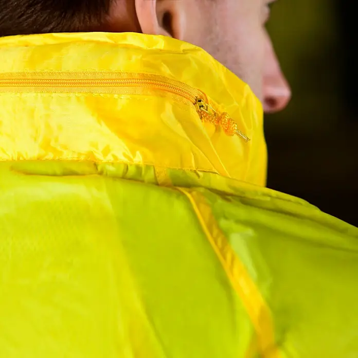 Regenbekleidung - L, Gelb - Nahaufnahme einer gelben Jacke mit Reißverschluss. Die Jacke ist wasserabweisend und hat einen hohen Kragen. Ideal für Outdoor-Aktivitäten.
