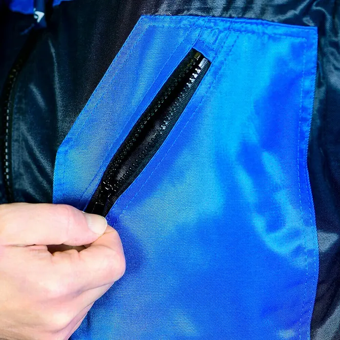 Elutex Piloten-Blouson 4in1 - Navy/Royalblau, XXL - Nahaufnahme einer blauen Jackentasche mit Reißverschluss, die mit einer Hand geöffnet wird.