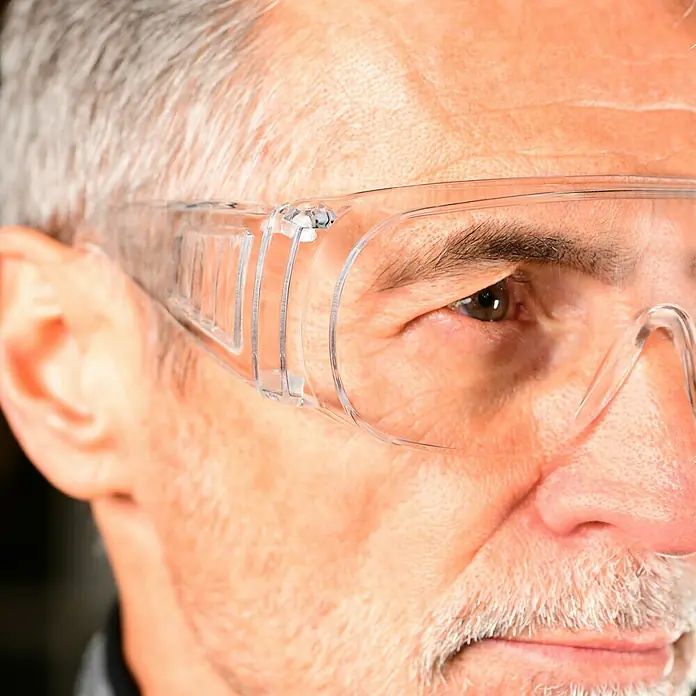 Zekler Schutzbrille 33 - Geeignet für: Brillenträger - Nahaufnahme eines Mannes mit transparenter Schutzbrille, die seine Augen vor äußeren Einflüssen schützt.