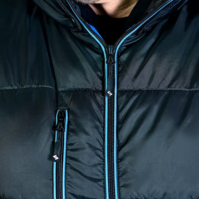 HD Concept Thermoweste - Schwarz/Blau, L - Detailansicht einer schwarzen Daunenjacke mit blauem Reißverschluss und dem Logo des Herstellers.