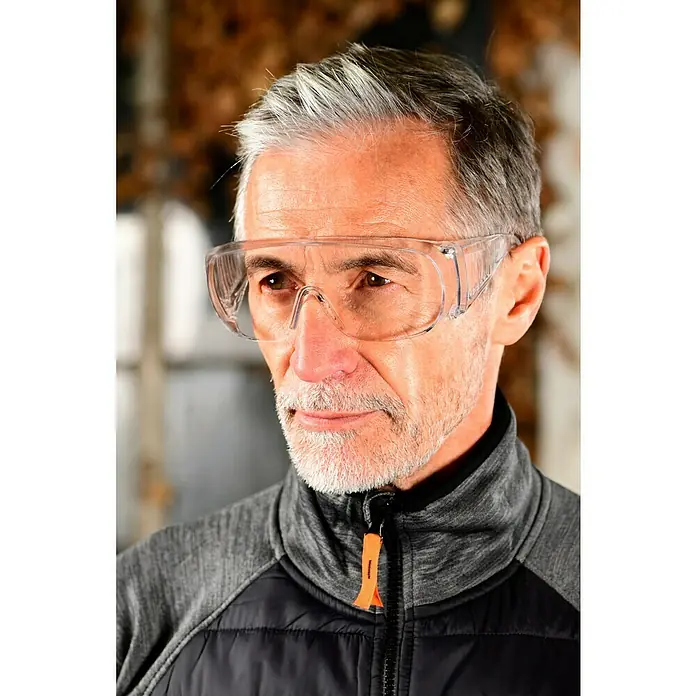Zekler Schutzbrille 33 - Geeignet für: Brillenträger - Nahaufnahme eines Mannes mit einer Schutzbrille. Die Brille schützt seine Augen bei der Arbeit. Er trägt eine Jacke mit Reißverschluss.