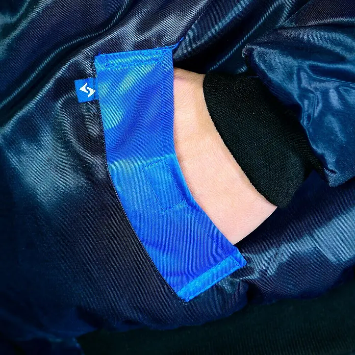 Elutex Piloten-Blouson 4in1 - Navy/Royalblau, XXL - Detailaufnahme einer blauen Jacke mit einer Tasche, in der eine Hand steckt, die einen Einblick in das schwarze Innenfutter gibt.