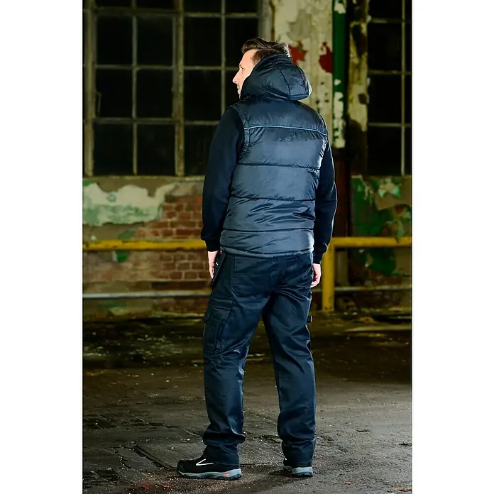 HD Concept Thermoweste - Schwarz/Blau, L - Ein Mann in Arbeitskleidung, mit einer schwarzen Weste und Cargohose. Die strapazierfähige Arbeitskleidung bietet Komfort und Schutz.