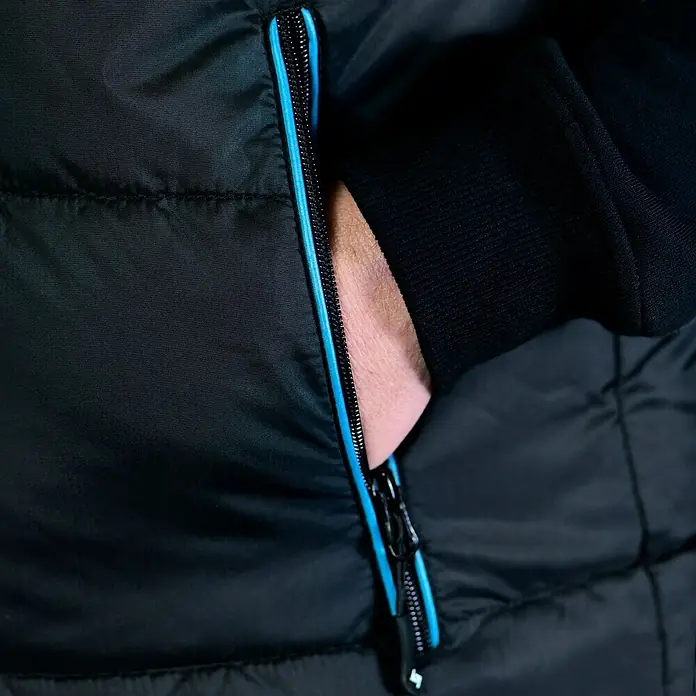 HD Concept Thermoweste - Schwarz/Blau, L - Detailaufnahme einer schwarzen Jacke mit blauem Reißverschluss, die die hochwertige Verarbeitung und das stilvolle Design hervorhebt.
