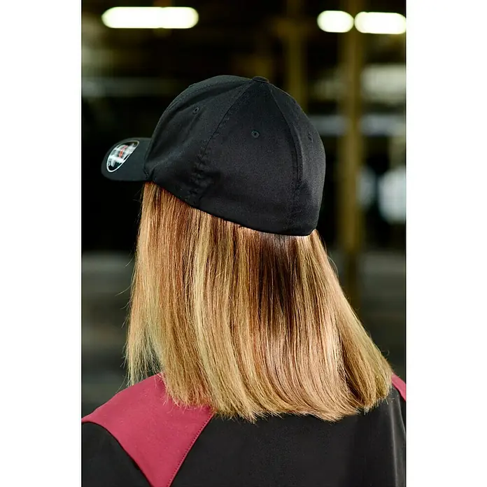 Flexfit Baseballkappe - Schwarz, S/M - Nahaufnahme einer Person mit einer schwarzen Baseballkappe, die ihr blondes Haar bedeckt. Ideal für Sport oder Freizeitaktivitäten.