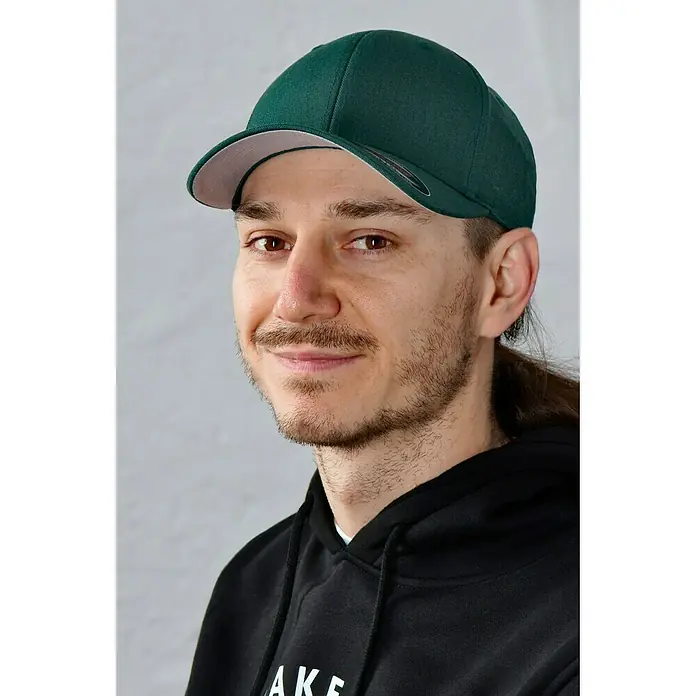 Flexfit Baseballkappe - Dunkelgrün, S/M - Porträt eines Mannes mit Bart, der eine grüne Kappe und einen schwarzen Hoodie trägt.