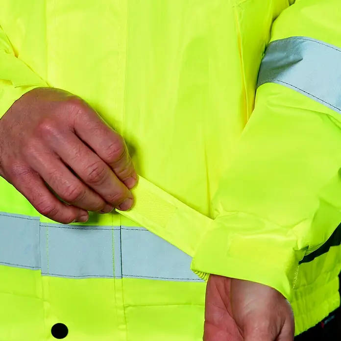 Scheibler Warnschutz-Jacke Blouson - Gelb, XL - Nahaufnahme einer gelben Warnschutzjacke, die mit einem verstellbaren Klettverschluss am Ärmel für optimalen Komfort ausgestattet ist.
