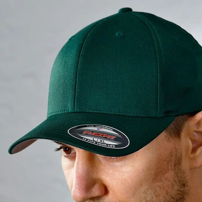 Flexfit Baseballkappe - Dunkelgrün, S/M - Nahaufnahme einer grünen Flexfit-Kappe mit gebogenem Schirm und einer schwarzen Flexfit-Logo-Applikation.