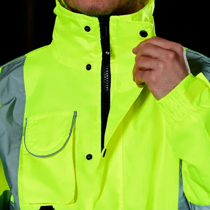 Scheibler Warnschutz-Jacke Blouson - Gelb, XL - Nahaufnahme einer gelben Warnschutzjacke mit Reißverschluss und Knöpfen, die Schutz und Sichtbarkeit bietet.