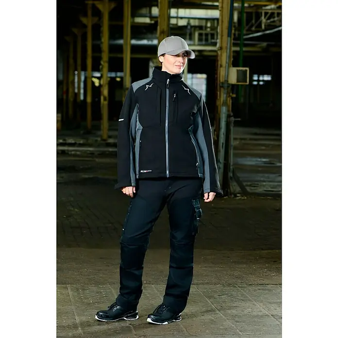 Flexfit Gorra - Gris, S/M - Una mujer con ropa de trabajo que incluye una chaqueta y pantalones negros, diseñados para un aspecto profesional y protección en el trabajo.