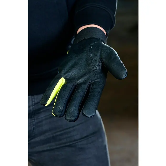 Guide Arbeitshandschuhe 775 W - Schwarz/Grau, 10 - Nahaufnahme eines Mannes mit einem schwarzen Lederhandschuh mit neongelben Akzenten, ein stilvolles und schützendes Accessoire.