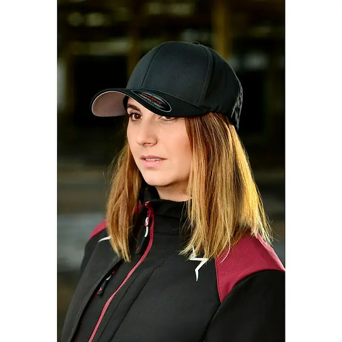 Flexfit Baseballkappe - Schwarz, S/M - Frau mit schwarzer Flexfit-Kappe und schwarzer Jacke mit burgunderroten Ärmeln.