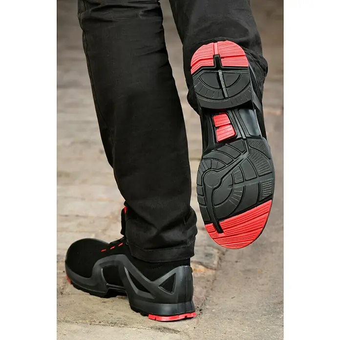 Uvex Sicherheitshalbschuh 1 - 42, Schutzklasse nach EN ISO 20345: S1P, Schwarz/Rot - Ein Paar schwarze Arbeitsschuhe mit roten Sohlen stehen auf einem grauen Untergrund. Die Sohle des einen Schuhs ist gut sichtbar.