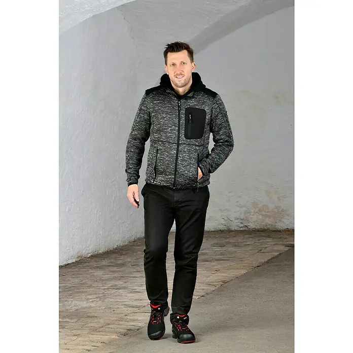 Uvex Sicherheitshalbschuh 1 - 42, Schutzklasse nach EN ISO 20345: S1P, Schwarz/Rot - Ein Mann trägt eine Kapuzenjacke mit Reißverschluss, schwarze Hose und Arbeitsschuhe in einem hellen Raum.
