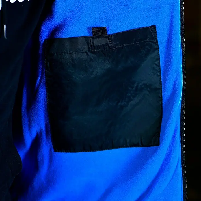 HD Concept Thermoweste - Schwarz/Blau, L - Detailaufnahme einer Jacke mit einer Innentasche aus schwarzem Stoff und blauem Fleecefutter, die Funktionalität und Komfort vereint.
