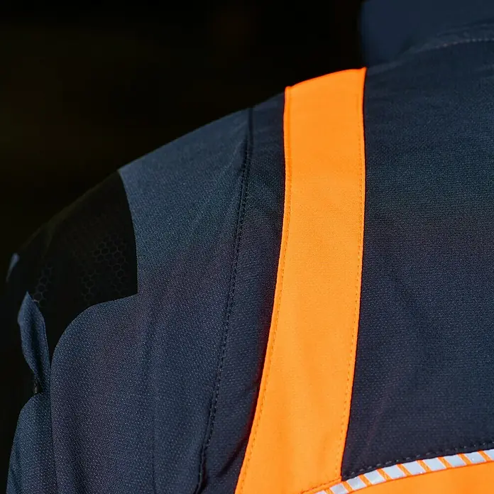 Bullstar Multifunktionsjacke Proximo - Orange/Anthrazit, L - Detailaufnahme einer dunkelgrauen Sicherheitsjacke mit einem markanten, vertikalen, orangefarbenen Reflexstreifen.