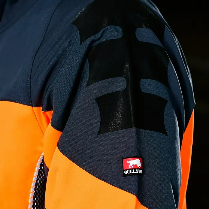Bullstar Multifunktionsjacke Proximo - Orange/Anthrazit, L - Nahaufnahme einer zweifarbigen Arbeitsjacke mit dem Markenlogo "BULLSTAR" am Ärmel.