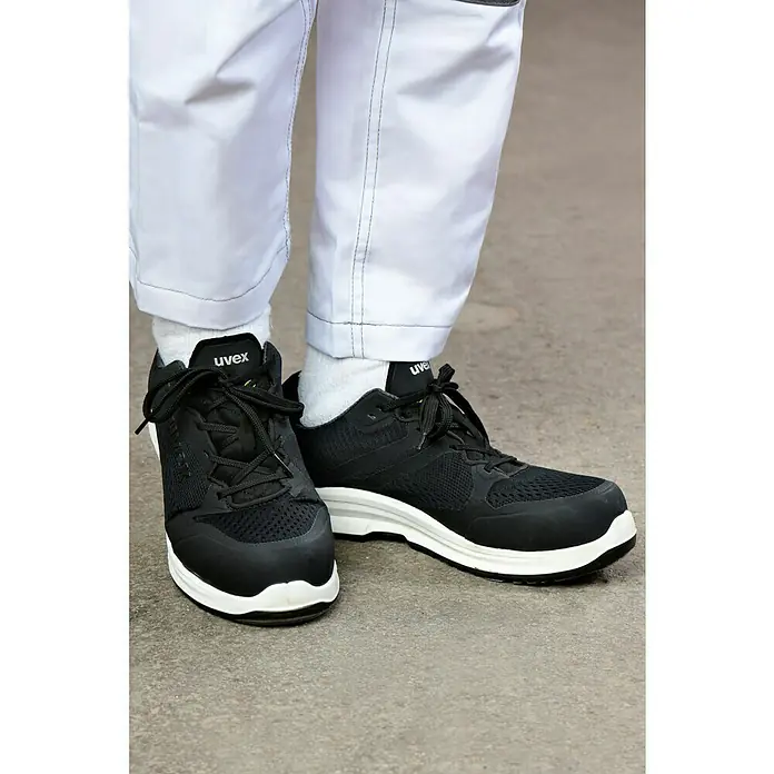 Uvex Sicherheitshalbschuh 1 Sport - 44, Schutzklasse nach EN ISO 20345: S1 - Hier sind schwarze Uvex-Sicherheitsschuhe mit weißen Sohlen zu sehen. Sie sind bequem und bieten Schutz bei der Arbeit.