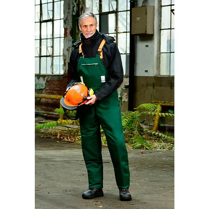 Bullstar Forst-Schutzhelm Peltor Master - Orange - Ein Mann in grüner Arbeitskleidung hält einen orangefarbenen Schutzhelm. Die Kleidung und der Helm sind die Hauptprodukte.