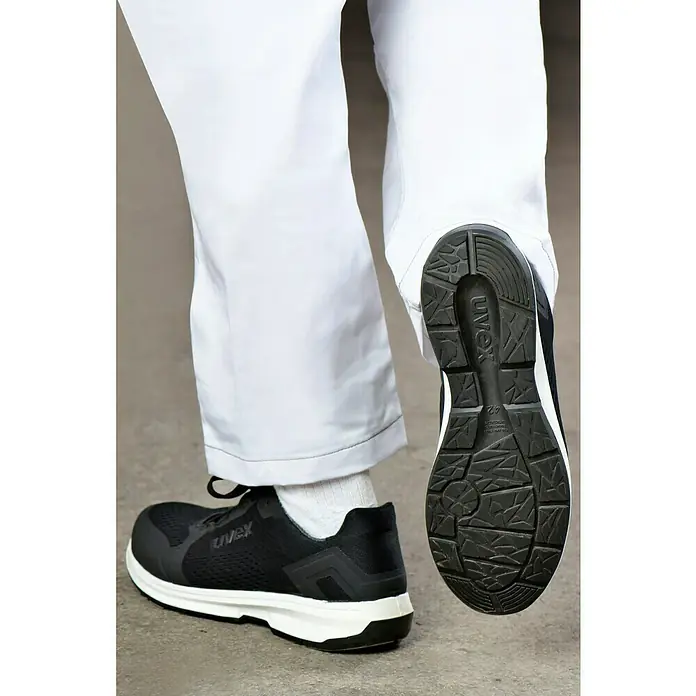 Uvex Sicherheitshalbschuh 1 Sport - 44, Schutzklasse nach EN ISO 20345: S1 - Aufnahme von Uvex-Sicherheitsschuhen, Modell 1, mit schwarzem Obermaterial und weißer Sohle, die Komfort und Schutz am Arbeitsplatz bieten.