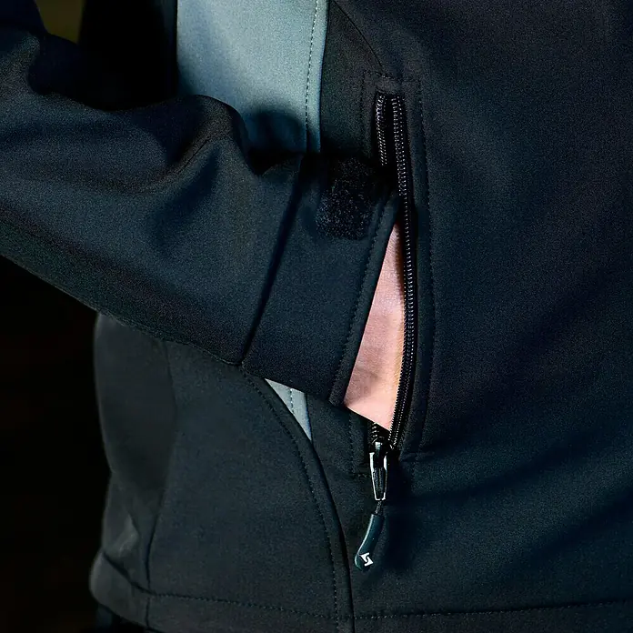HD Concept Softshell-Jacke Fit - Schwarz/Grau, XXL - Nahaufnahme einer schwarzen Softshelljacke mit Reißverschlusstasche und verstellbarem Ärmel.