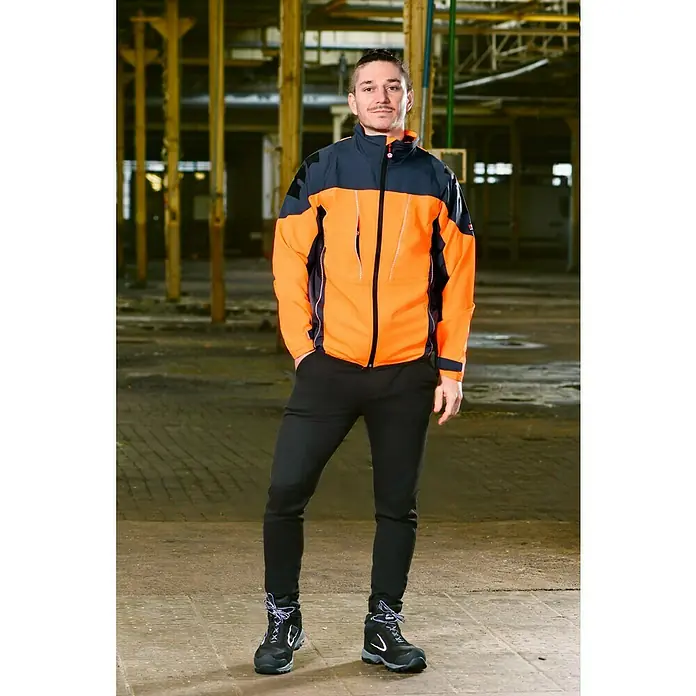 Bullstar Multifunktionsjacke Proximo - Orange/Anthrazit, XL - Ein Mann posiert in einer orangefarbenen und marineblauen Arbeitsjacke, schwarzen Hosen und Arbeitsschuhen.