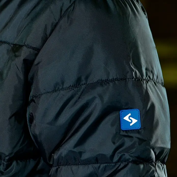 HD Concept Thermojacke - XL, Blau/Schwarz - Detailaufnahme einer schwarzen, gesteppten Jacke mit blauem Logo-Patch am Ärmel. Ideal für kühle Tage.