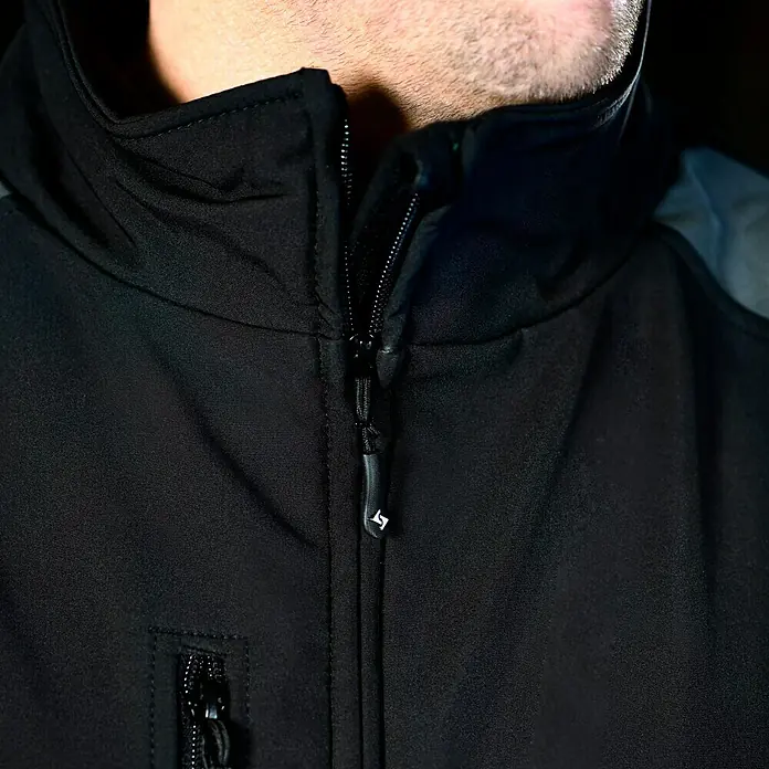 HD Concept Softshell-Jacke Fit - Schwarz/Grau, XXL - Nahaufnahme einer schwarzen Jacke mit Reißverschluss und Kapuze. Die Jacke ist modern und funktional gestaltet.