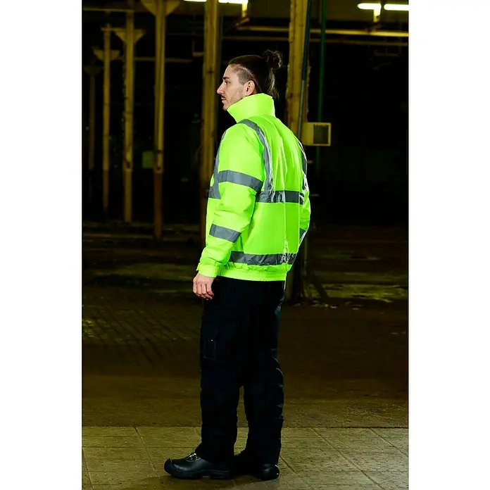 Scheibler Warnschutz-Jacke BlousonGelb, XXL - Ein Mann in Arbeitskleidung mit einer neongelben Jacke und schwarzen Hosen, die die Sicherheitsausrüstung hervorheben.