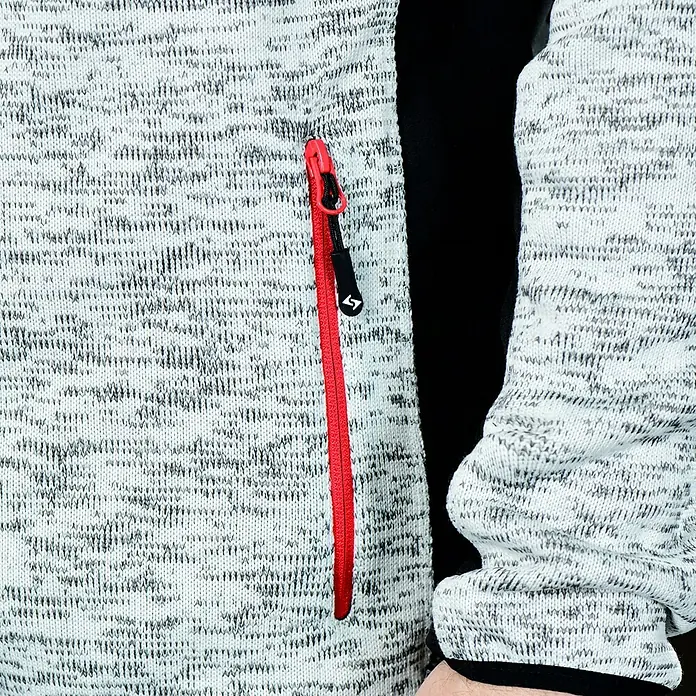 HD Concept Strickjacke Professional - Grau/Schwarz, XL - Nahaufnahme einer melierten Fleecejacke mit rotem Reißverschluss und Logo-Detail, ideal für Outdoor-Aktivitäten.