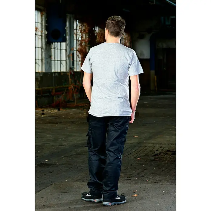 T-Shirt Handcrafter - Grau, L - Eine Person von hinten, mit grauen T-Shirt, schwarzen Arbeitshosen und Sicherheitsschuhen in einer Industriehalle.