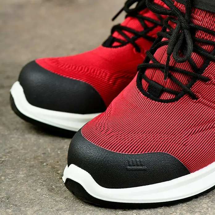 Steitz Secura Sicherheitshalbschuh CP 4360 SF - Schuhgröße: 39, S3 - Nahaufnahme von roten Laufschuhen mit schwarzen Schnürsenkeln und Zehenschutz auf rauem Untergrund.