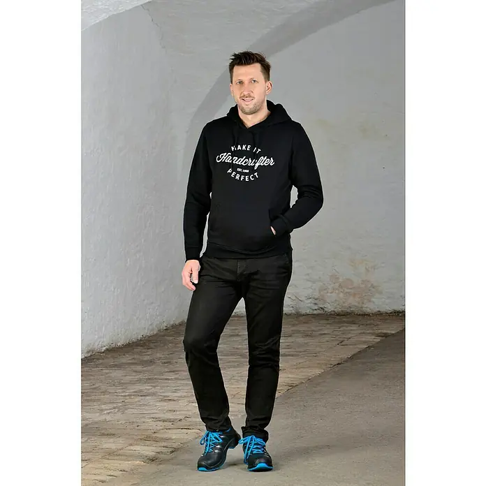 Uvex 2 Trend Sicherheitshalbschuh S3 - 42, Schutzklasse nach EN ISO 20345: S3, Schwarz/Blau - Schwarzer Kapuzenpullover mit dem Aufdruck "Make it Hardcrafter Perfect Est. 1960" kombiniert mit schwarzen Jeans und blauen Schuhen.