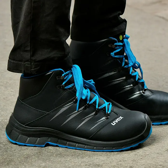 Uvex 2 Trend Sicherheitsstiefel S3 - 42, Schutzklasse nach EN ISO 20345: S3, Schwarz/Blau - Nahaufnahme von schwarzen Uvex-Sicherheitsstiefeln mit blauen Schnürsenkeln und Sohlen, die robust und langlebig sind.
