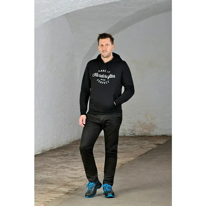 Uvex 2 Trend Sicherheitshalbschuh S3 - 42, Schutzklasse nach EN ISO 20345: S3, Schwarz/Blau - Ein Mann trägt einen schwarzen "Hardcrafter"-Hoodie, schwarze Hosen und blaue Schuhe in einem Tunnel.
