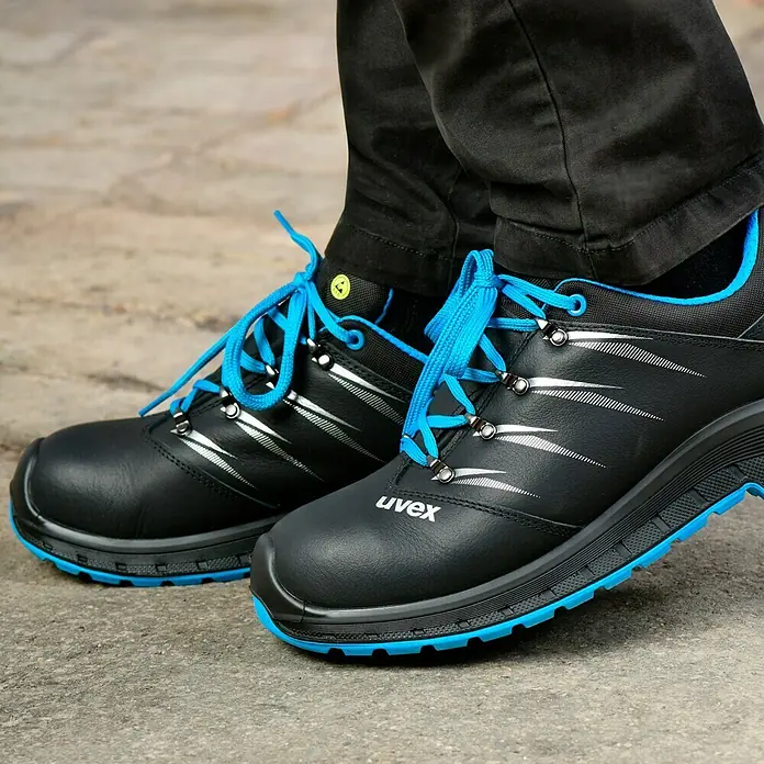 Uvex 2 Trend Sicherheitshalbschuh S3 - 42, Schutzklasse nach EN ISO 20345: S3, Schwarz/Blau - Nahaufnahme von Uvex Arbeitsschuhen mit blauen Schnürsenkeln und Akzenten, die auf Sicherheit und Stil ausgelegt sind.