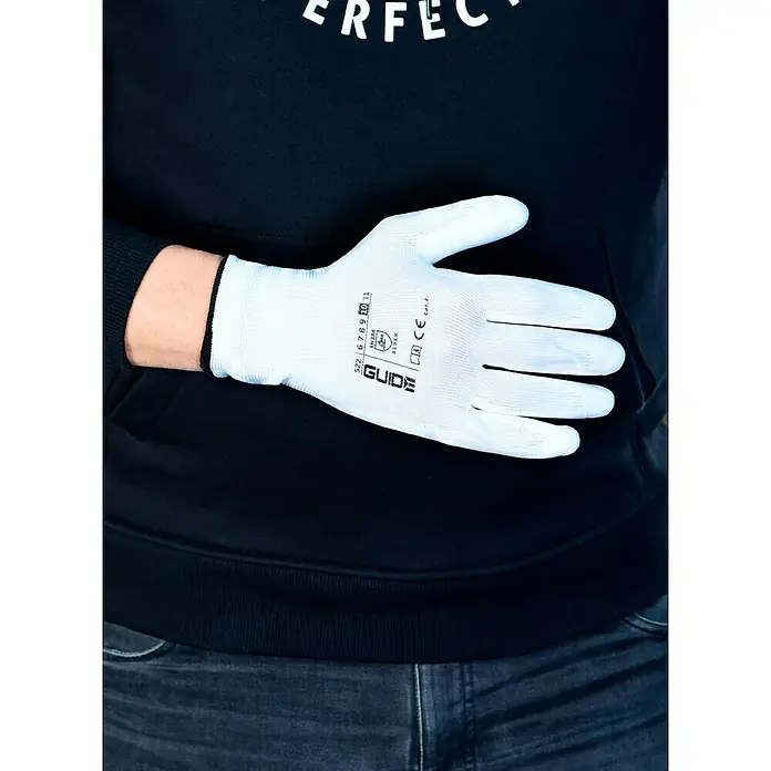 Guide Arbeitshandschuhe 522 - Handschuhgröße: 10, Weiß - Nahaufnahme eines weißen Guide-Schutzhandschuhs mit schwarzen Aufdruck auf einer Hand vor einem schwarzen Hoodie und Jeans.